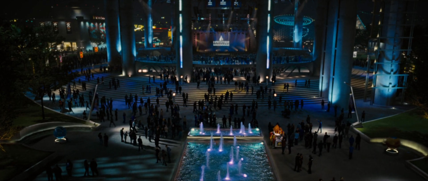 Nighttime exterior of the Stark Expo main entrance and fountains.
