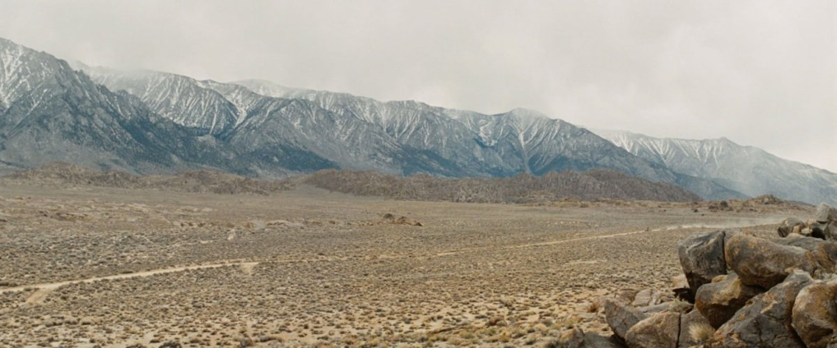 An ongoing desert with snow peaked mountains behind it.