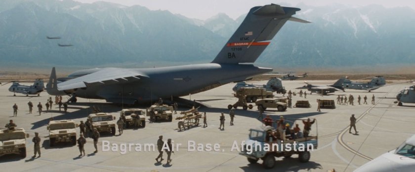 Airplane and military vehicles on a tarmac at Bagram Air Force Base.