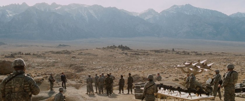 A group of military soldiers gather for missile test in the desert near some hills.