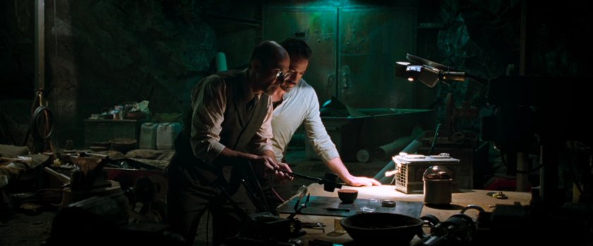 Tony Stark and Yinsen work in a dark cave.