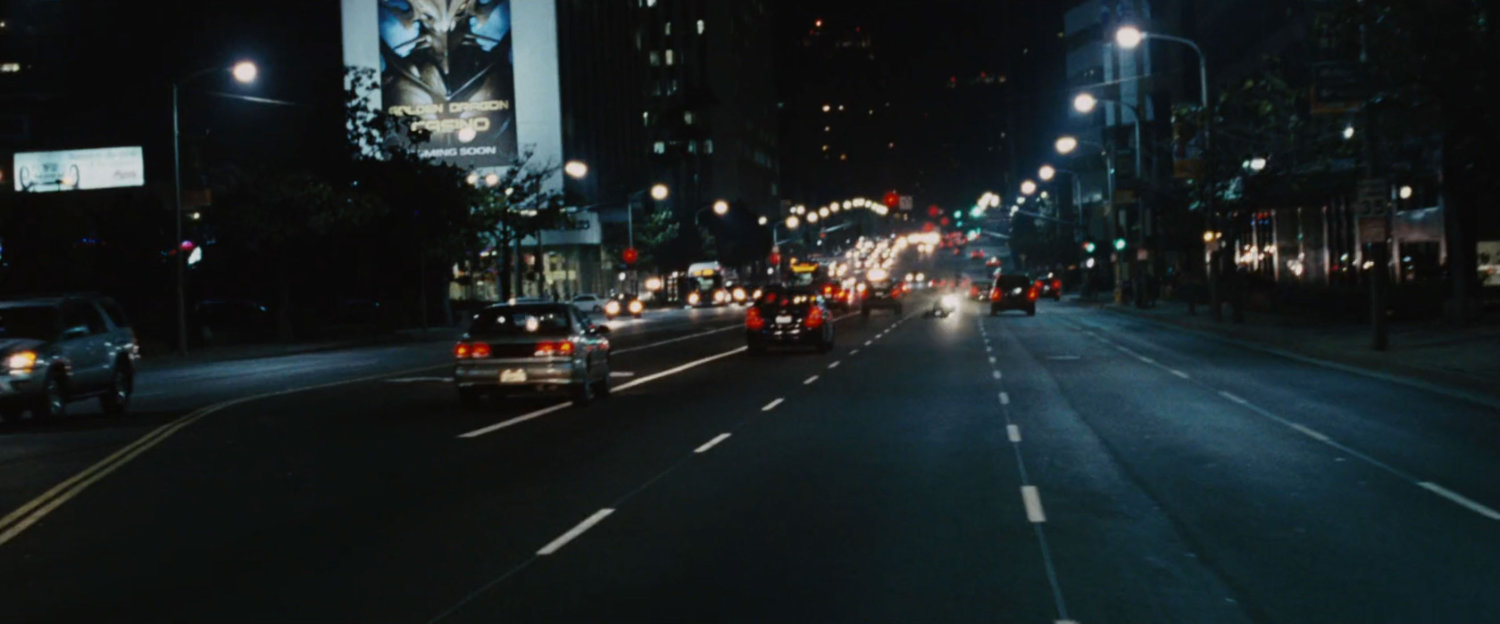 Iron Man races above a Westwood street at night.