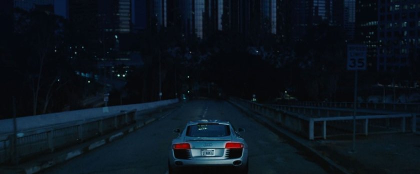Silver Audi drives into Los Angeles at dusk.