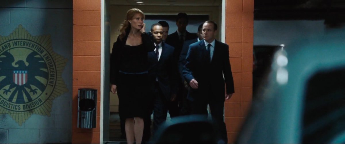 Pepper Potts and Agent Coulson exit an elevator into an underground SHIELD garage.