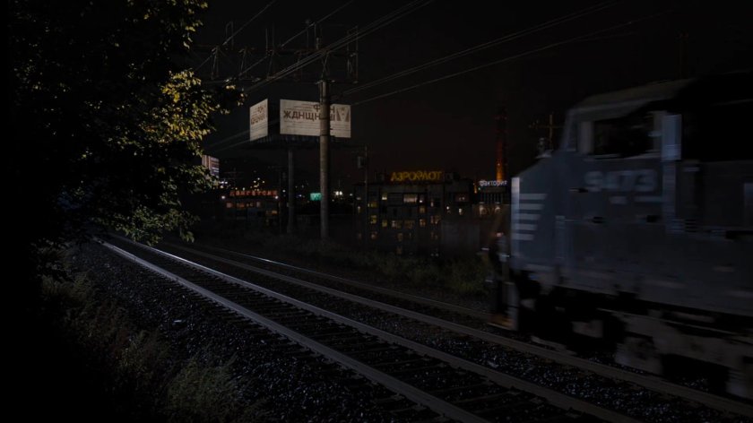 A train driving past an old factory building in Russia.