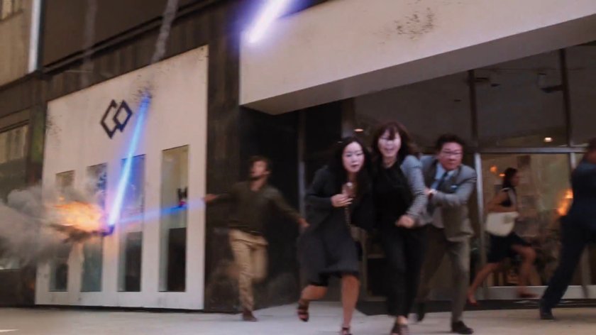 Civilians dodge a laser blast into a storefront.