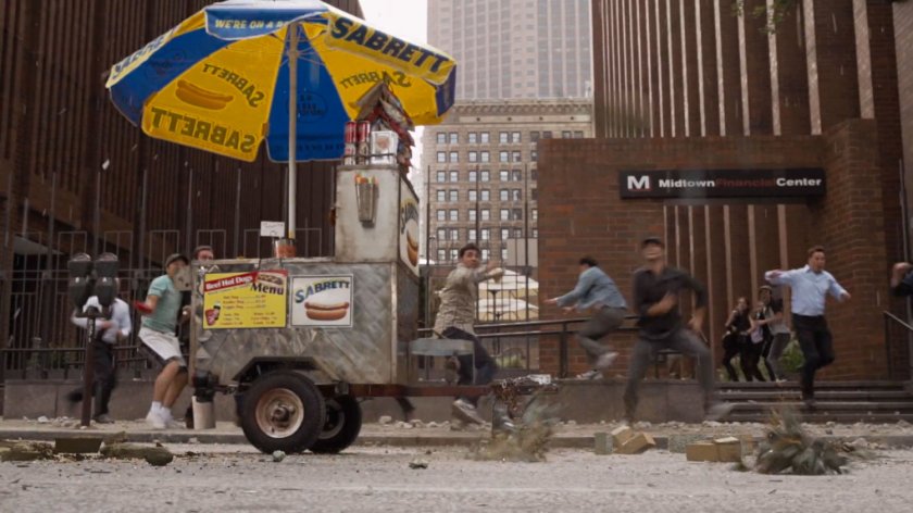 Civilians run in panic on the sidewalk near a hot dog cart.