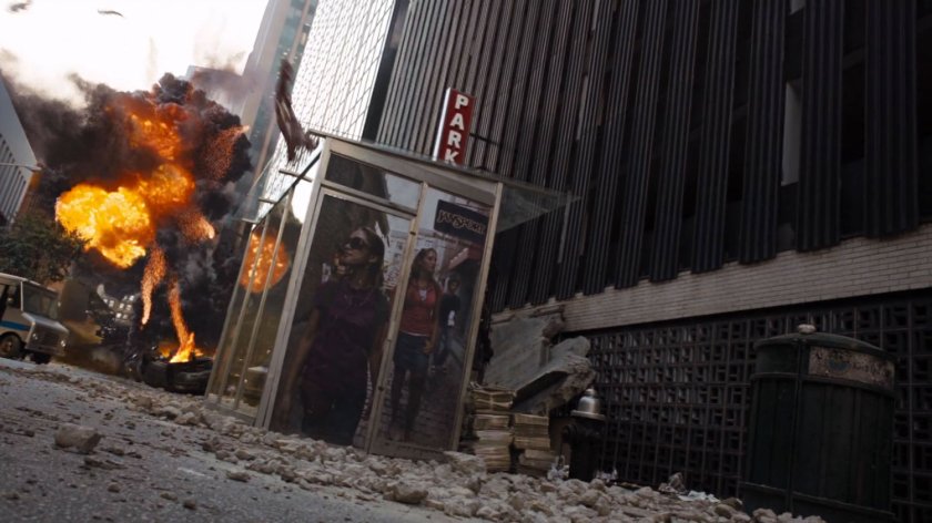 An explosion behind a bus shelter in a debris strewn street.