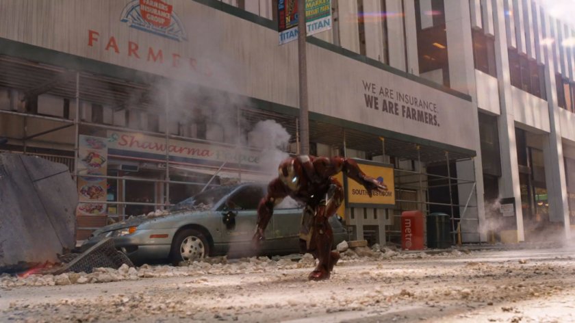 Iron Man on a debris filled New York street, behind him a shawarma restaurant.
