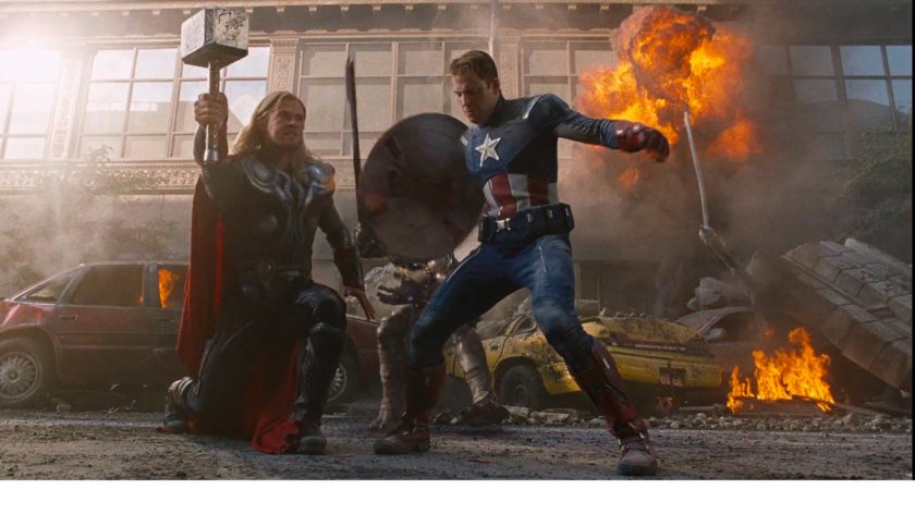 Thor and Captain America pose in front of flaming debris.