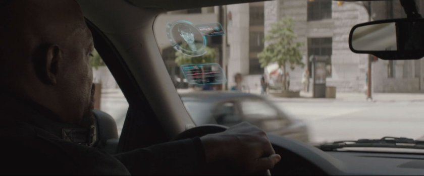 Nick Fury behind the wheel of SUV, driving on street.