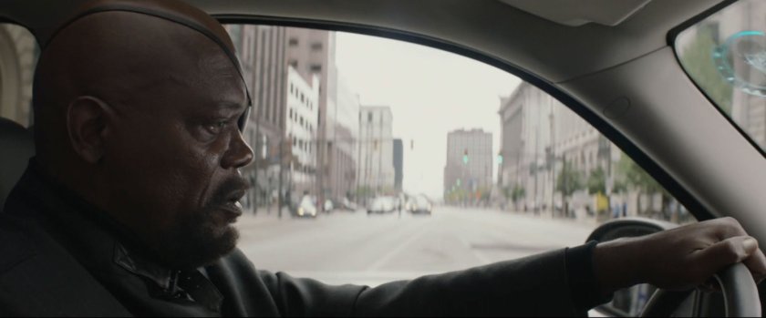 Nick Fury behind the wheel of SUV, driving on street.