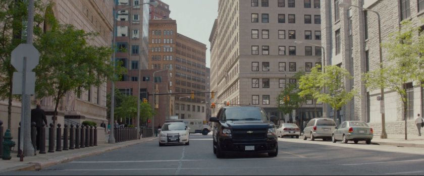 A police car pulls up along side a black SUV at an intersection.