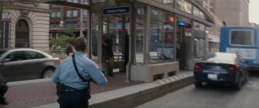 Police officer runs towards metro entrance.