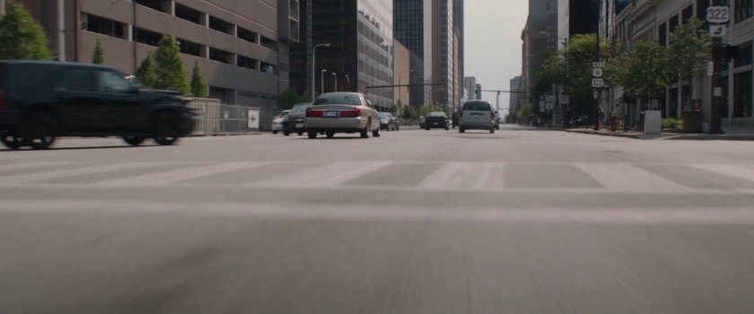 A black SUV makes a quick turn onto wider city street.