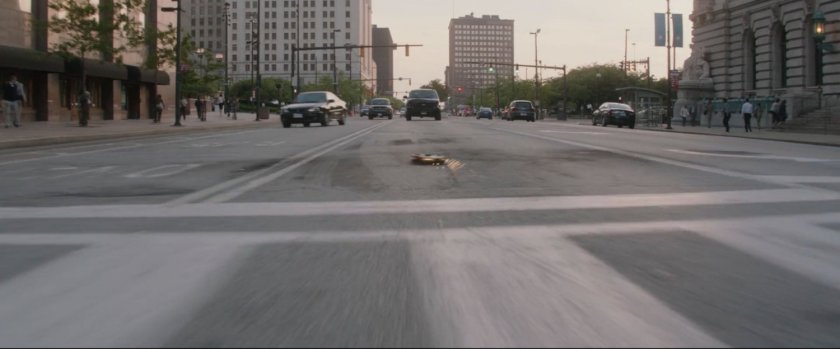 Black SUV drives towards explosive device on pavement.