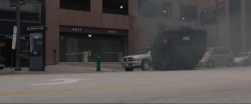 Black SUV upside down outside parking garage.