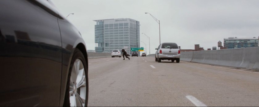A man in the middle of a busy freeway lane.