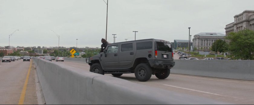 Man sitting on hood of HumVee on a freeway overpass.