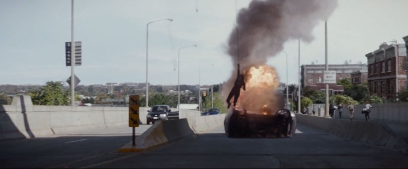 Natasha swing off a freeway overpass by a burning car.