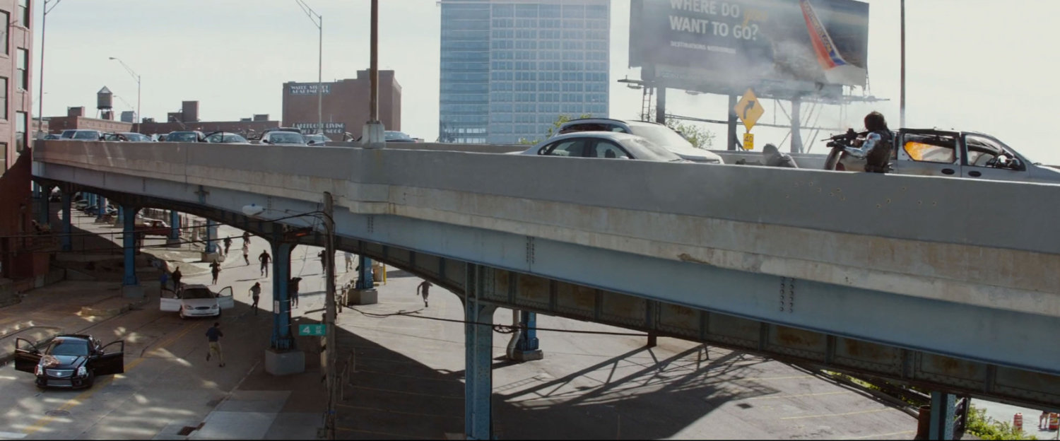 A shootout on a crowded freeway overpass, as civilians run away.