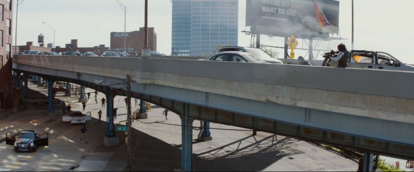 A shootout on a crowded freeway overpass, as civilians run away.