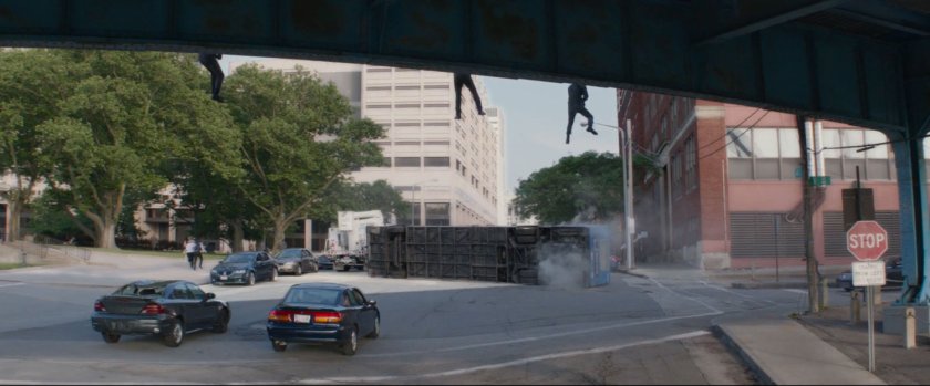 Three men repel off a freeway overpass to the street below.