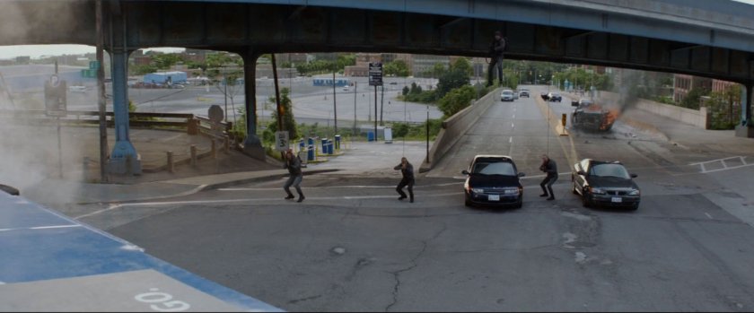Three men under an overpass fire machine guns at a bus.