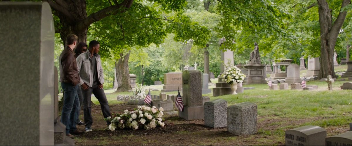 Steve and Sam stand over a gravestone at a cemetery.
