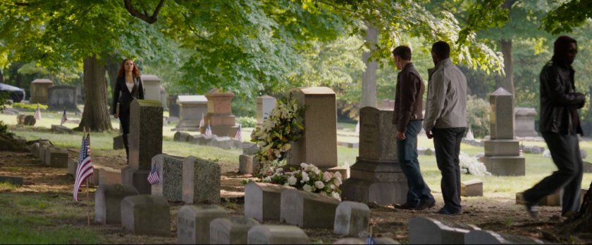 Steve and Sam stand over a gravestone at a cemetery.