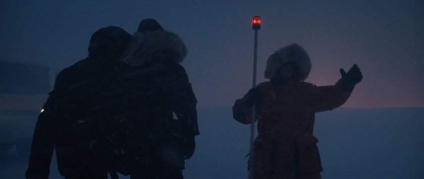 Three men in parkas in a snow storm at dusk.