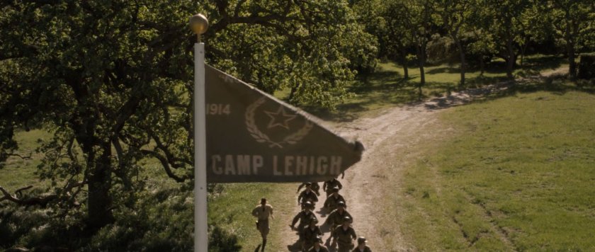 Soldiers jog past flagpole with Camp Lehigh flag.