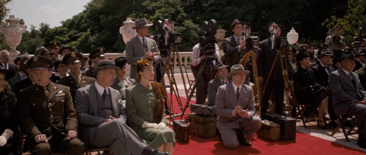 Audience and press gather for a press conference.