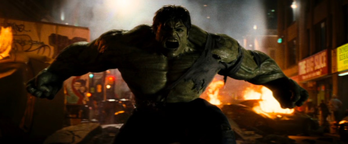 The Hulk roars in anger in front of flaming wreckage.
