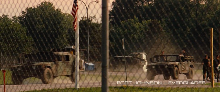 Military trucks outside a chain link fence. Text: Fort Johnson Everglades.