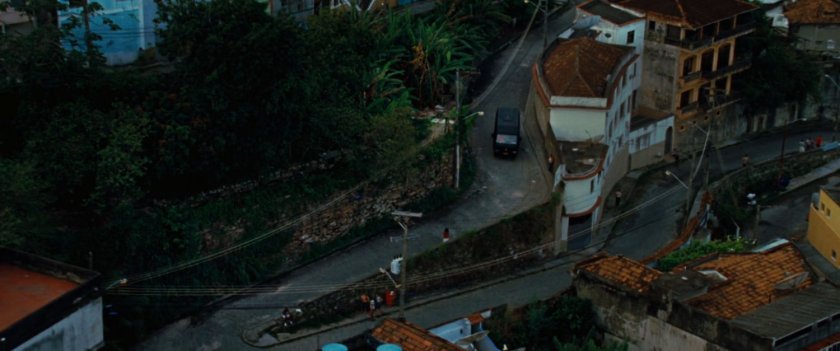 A van drives on a twisty favela street.