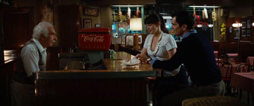 Stanley talking to Betty Ross inside pizza parlor.