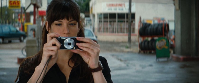 Betty Ross taking a picture of someone off screen, near a gas station.