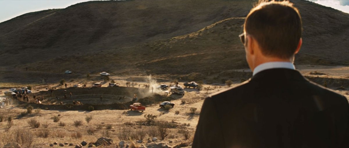 Agent Coulson overlooks a giant crater near a desert hill.