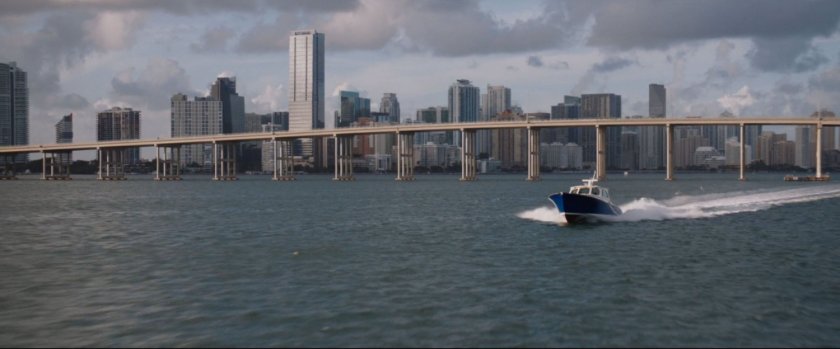 Speedboat crusing along water with bridge and Miami in background.