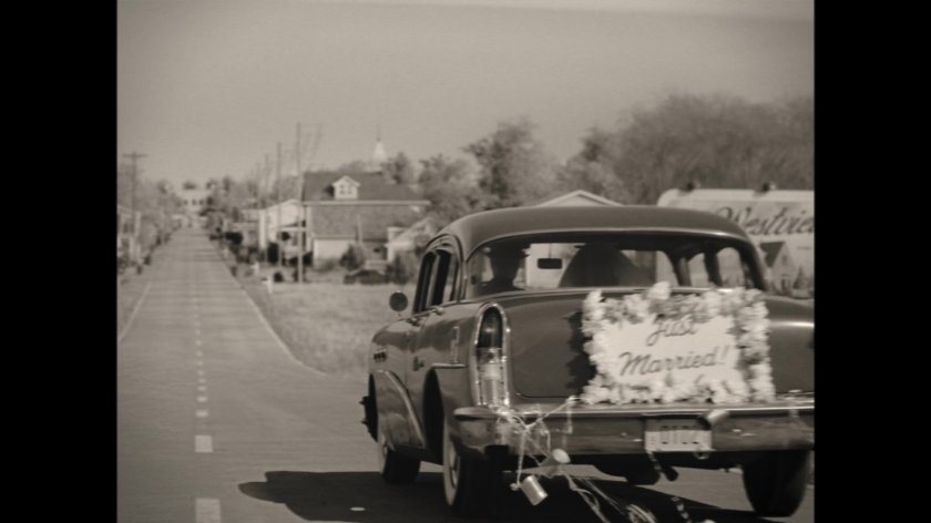 A 1950s car with "Just Married" sign on back drives into the town of Westview.