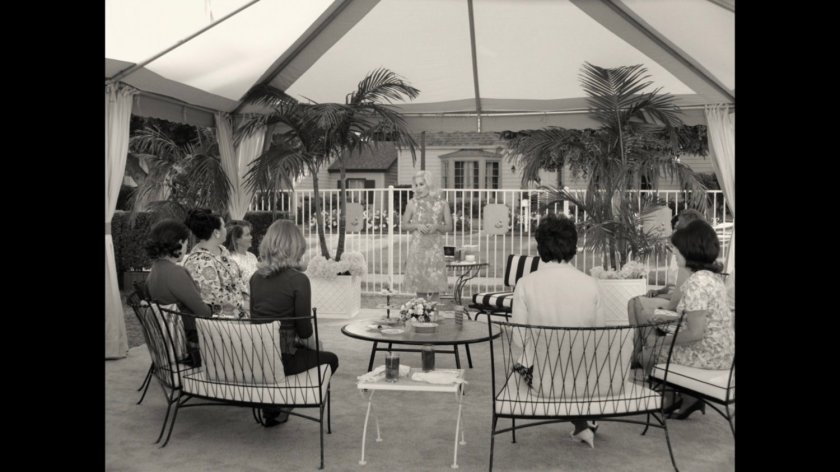 A group of women gather under a tent by a neighborhood swimming pool.