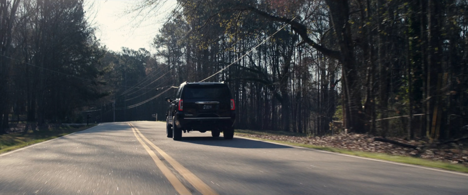 Black SUV on a treelined road.