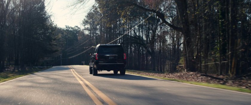 Black SUV on a tree-lined road.