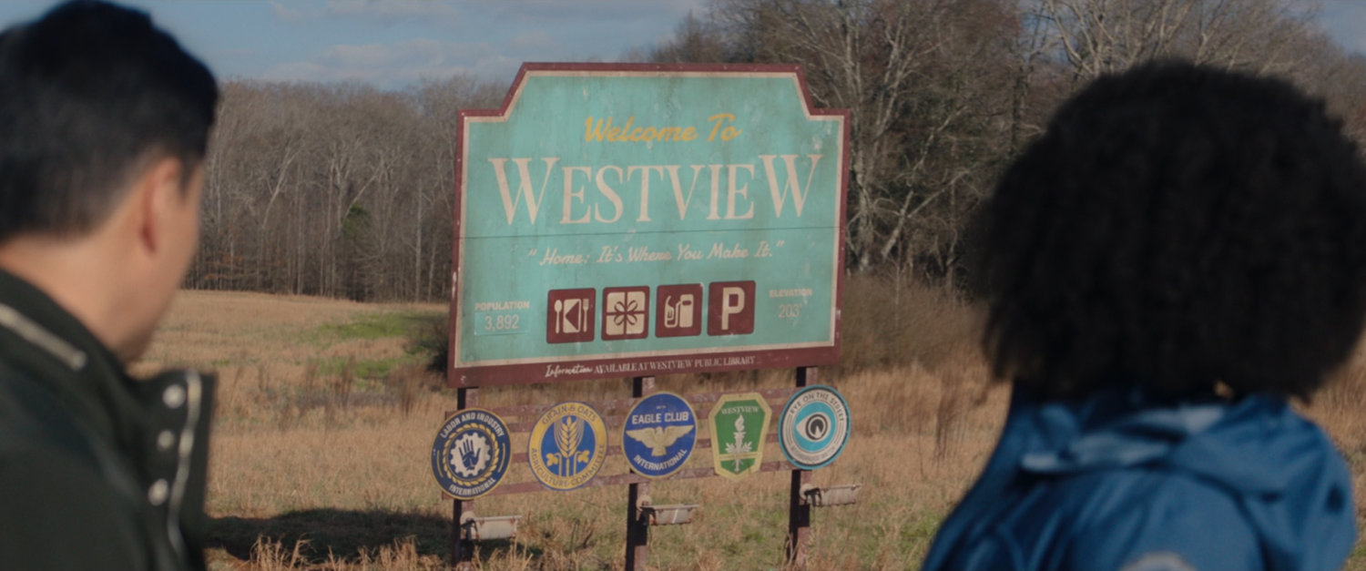 Monica and Jimmy look at "Welcome to Westview" sign.