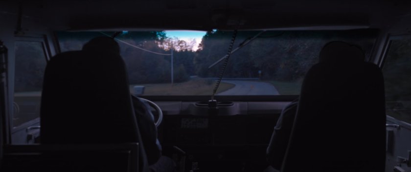 Interior POV from armored truck on dusky road.