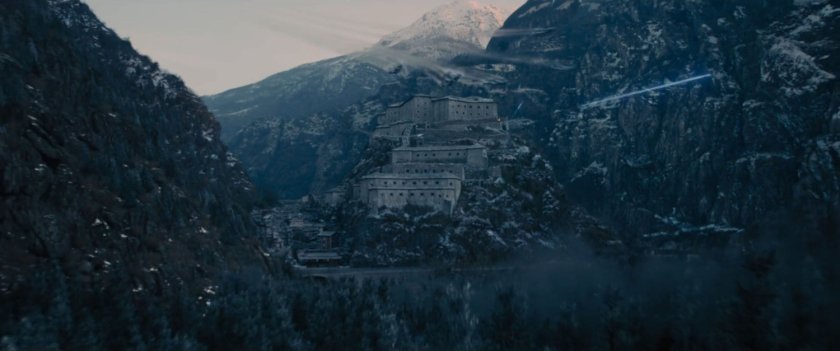 A giant castle on top of a snowy mountain in a valley.