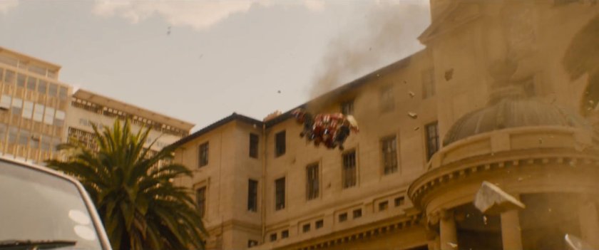 The Hulkbuster flies towards the top of a building.