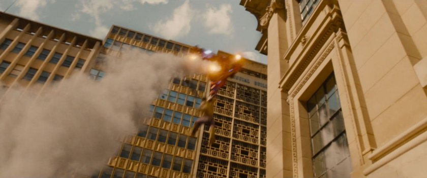 The Hulkbuster flies towards the top of a building.