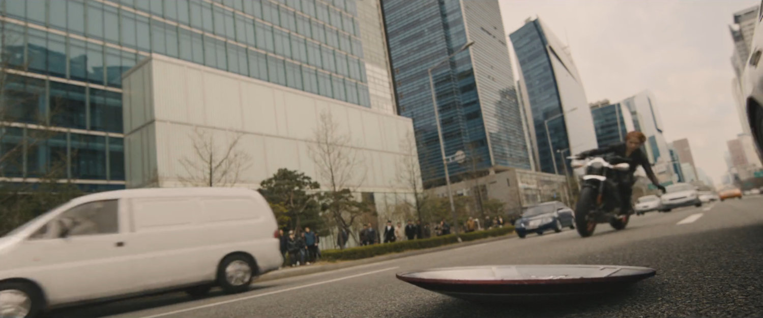 Black Widow picking up Cap's shield on a Seoul Korea street.
